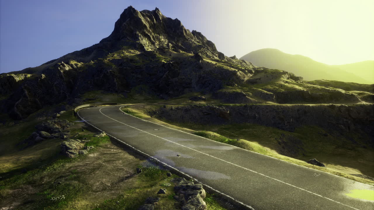 Scenic winding road leading towards a majestic mountain at sunrise