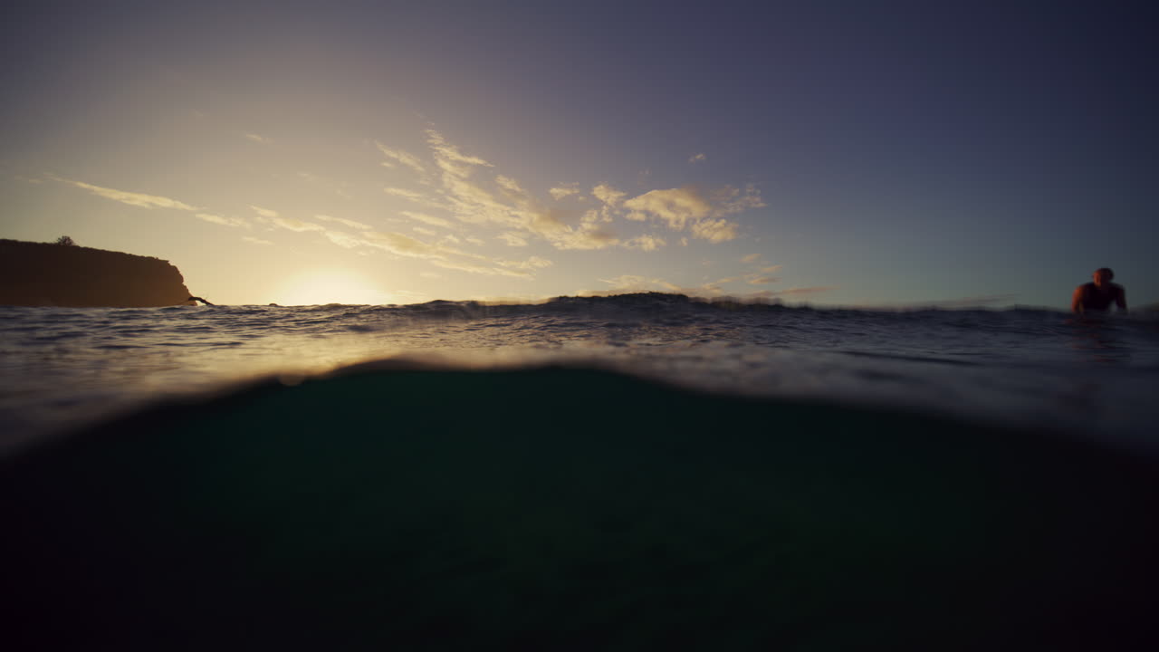 Surfers paddle back out to crowd as they wait for waves, view from underwater