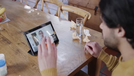 caucasian man holding medication making video call using tablet, slow motion