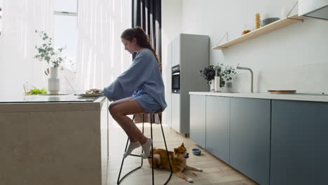 young woman working on her laptop at home next to her dog 8