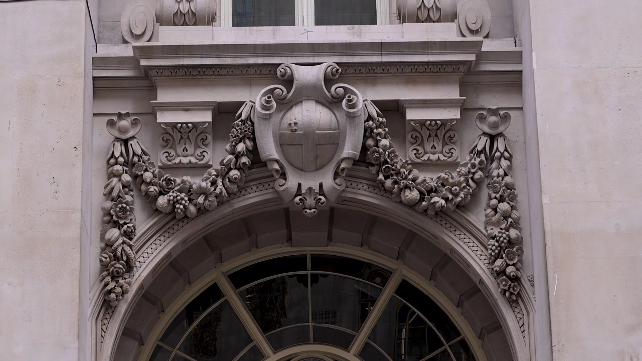 Ghirlande di pietra ornate e lo stemma della City di Londra si trovano sopra una finestra ad arco sulla facciata del Royal Exchange
