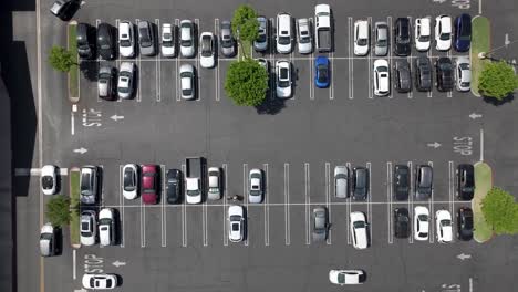 a busy parking lot in daytime - straight down rising aerial view