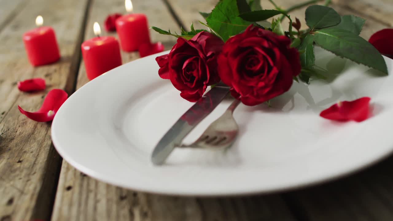 Candles and red roses on plate on wooden background at valentine's day