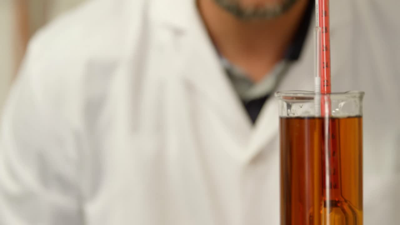 4k 측정 실린더에서 액체를 검사하는 남성 노동자