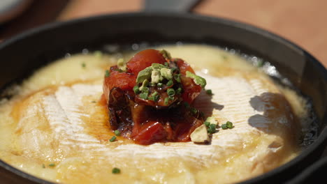 sprinkling chopped spring onions on top of nutritious provoleta with tomatoes