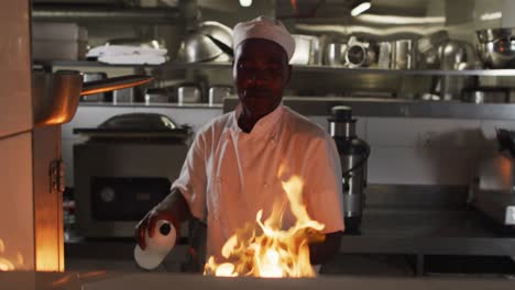 African-american-male-chef-frying-in-pan-in-restaurant-kitchen