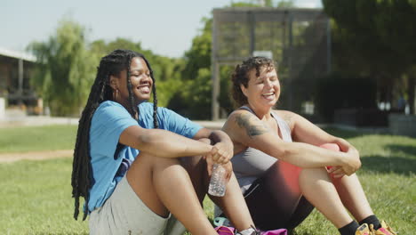 side view of smiling friends resting on lawn after workout