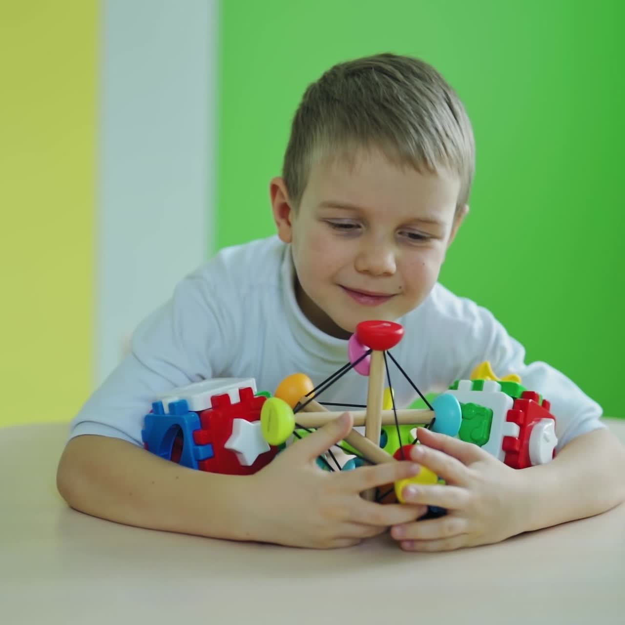 Happy little boy with toys.Bright toys on the table. Cute child is captures all plastic toys on the colorful room background. Slow motion.