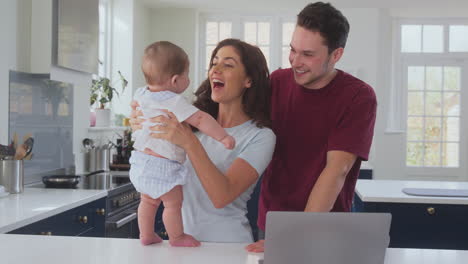 Loving-Transgender-Family-With-Baby-At-Home-Together-With-Laptop-On-Kitchen-Counter