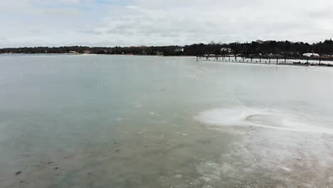 A-low-drone-flight-over-a-frozen-harbor-at-the-edge-of-a-coastal-village-on-the-Atlantic-Ocean