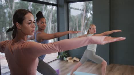 Mujeres-Diversas-Enfocadas-Estirándose-Juntas-En-Colchonetas-En-Clase-De-Yoga-Con-Entrenadora,-Cámara-Lenta