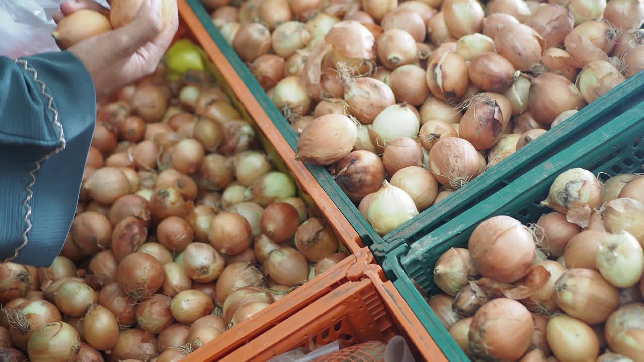 persona seleccionando cebollas en un mercado
