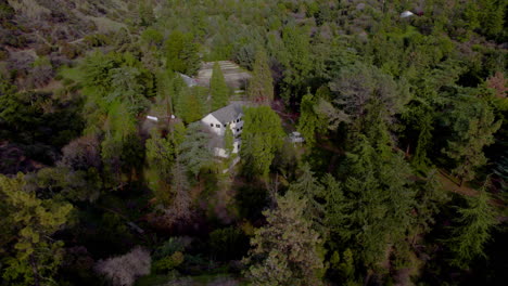 A-drone-shot-of-a-house-in-a-dense-forest-in-a-state-park,-rural-and-remote