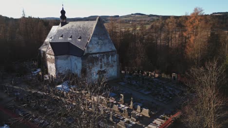 Vista-Aérea-De-Una-Iglesia-Gótica-Rodeada-De-Tumbas-En-El-Paisaje-De-Šumava-En-Velhartice