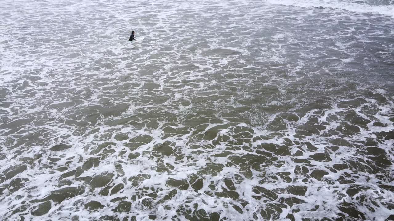 다음 서핑 세션을 위해 해변을 떠나 파도로 향하는 서퍼