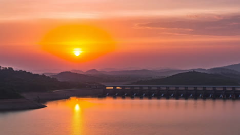 sunset over a dam and reservoir with hills