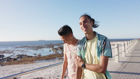 happy diverse gay male couple walking at promenade by the sea, slow motion