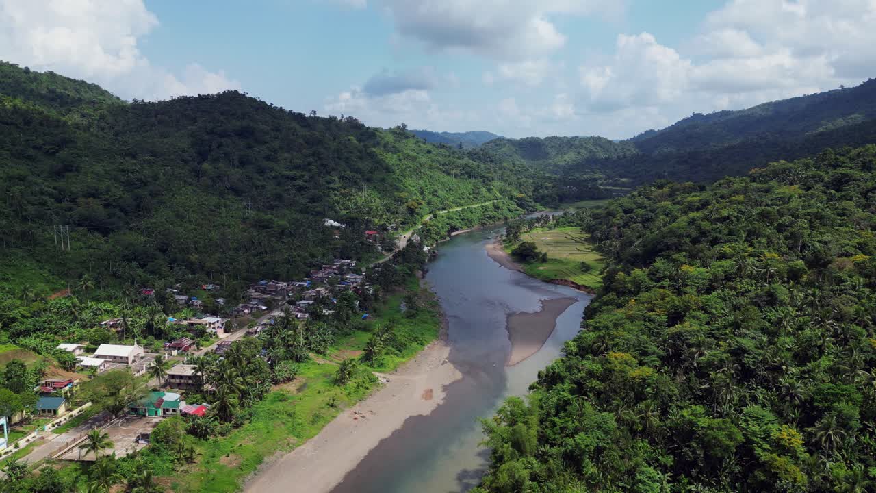 vista aérea ascendente de las casas de las aldeas tropicales a lo largo de un río ancho con orilla arenosa