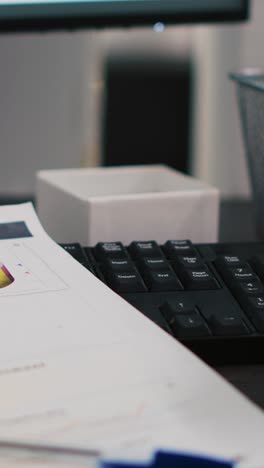 Vertical video Company files containing economic graphs and charts near coffee cup, close up
