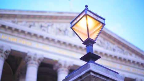 Lamppost-light-in-London-city-with-stone-monument-in-the-background,-clear-blue-dusk-sky