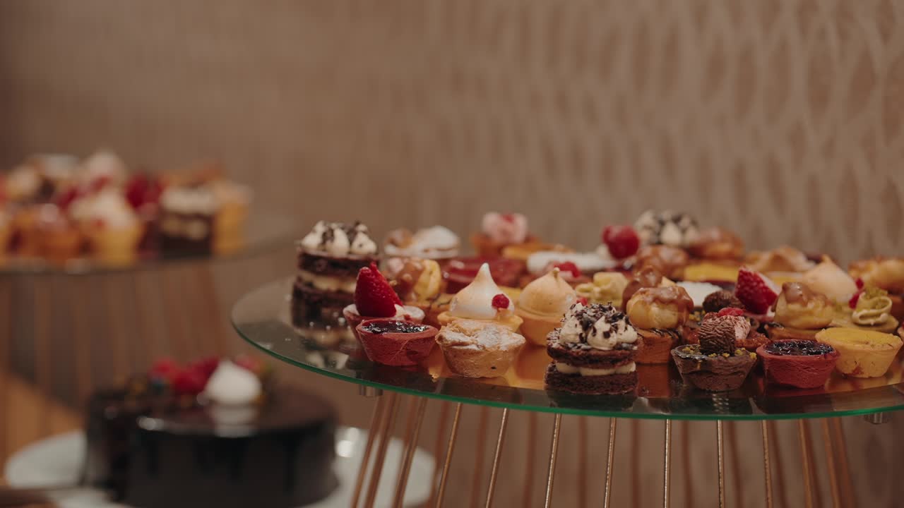 hand picks assorted mini desserts from upscale glass dessert table