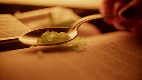 spoon with green crystals on an old book
