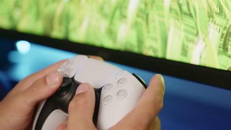 boy gaming on a playstation 5 with a ps5 controller in an rgb led room at night, side view close