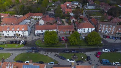 sideways aerial drone shot flying along beautiful old burnham market village main street on sunny and cloudy day in north norfolk uk