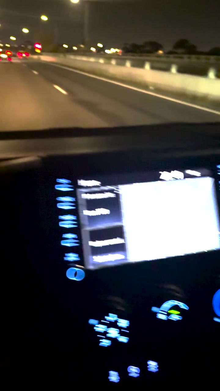 La telecamera a mano si sposta dagli indicatori illuminati del cruscotto alla strada buia dell'autostrada di notte.