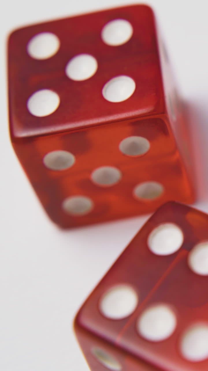 man shows and throws red transparent plastic dices with white spots on light background extreme close view