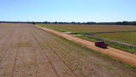 Luftaufnahme-Eines-Roten-Pickup-Trucks,-Der-Auf-Einer-Unbefestigten-Straße-In-Einem-Ländlichen-Farmgebiet-Von-Mississippi-Fährt-1