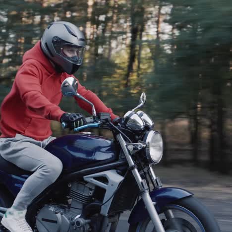 young motorcyclist quickly rides along the road along the forest