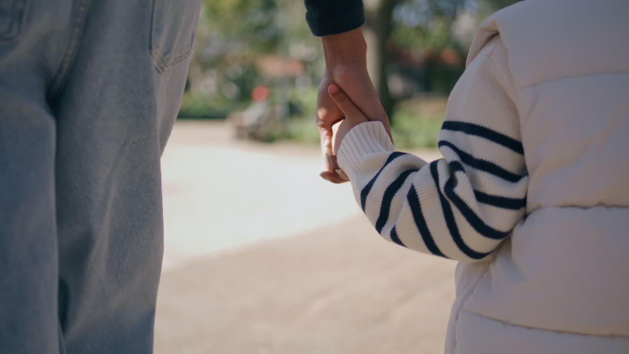 알려지지 않은 여성이 손을 잡고 작은 소녀가 가까이에서 공원을 고 있습니다.