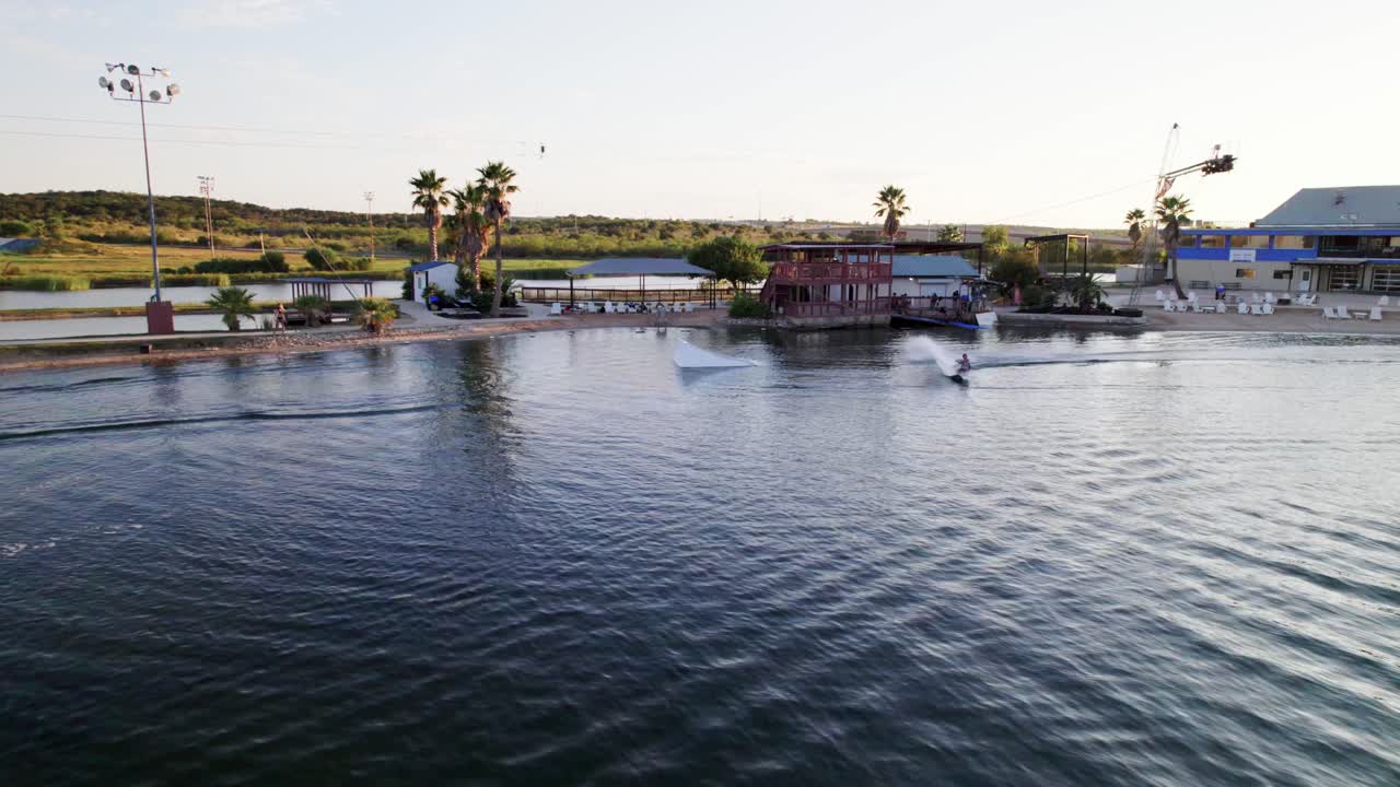 Aerial view of person wakeboarding in the summer during sunset at the lake