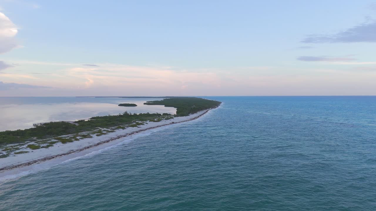 An aerial view of Isla Blanca, Quintana Roo, reveals a slender strip of white sand bordered by turquoise sea and calm lagoon waters