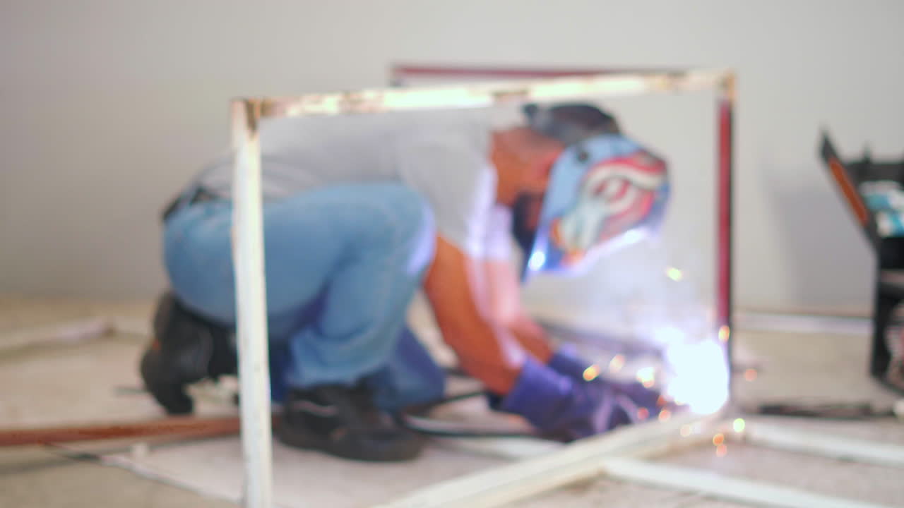 two middle age latin blacksmiths welding a metal frame with safety equipment