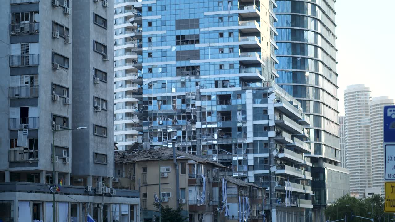 Static shot, residential high-rise, shattered windows, broken balconies, modern façade, debris on ground, urban damage, Tel Aviv