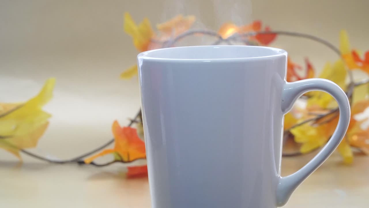 vapor saliendo de una taza de café o té con efecto bokeh y hojas doradas
