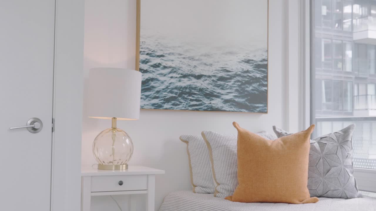 mostrando un cuarto de baño de condominio que tiene una cama individual dentro y una lámpara de noche a un lado y una fotografía de olas de agua en la pared