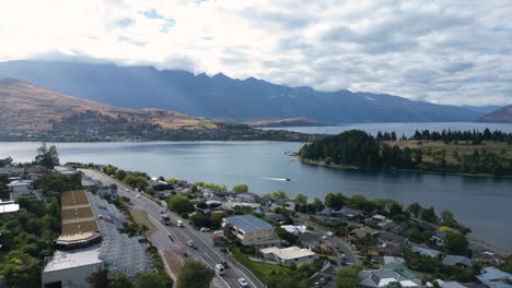 Aerial-view-over-Central-Queenstown,-New-Zealand-with-a-beautiful-lake-and-mountains-in-the-background