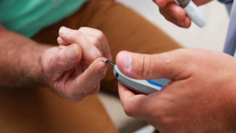 sección media del médico que examina el azúcar en la sangre del paciente mayor