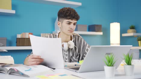 Estudiante-Mirando-El-Documento-En-Mano-Y-Tomando-Notas-En-La-Computadora-Portátil.-Tarea.