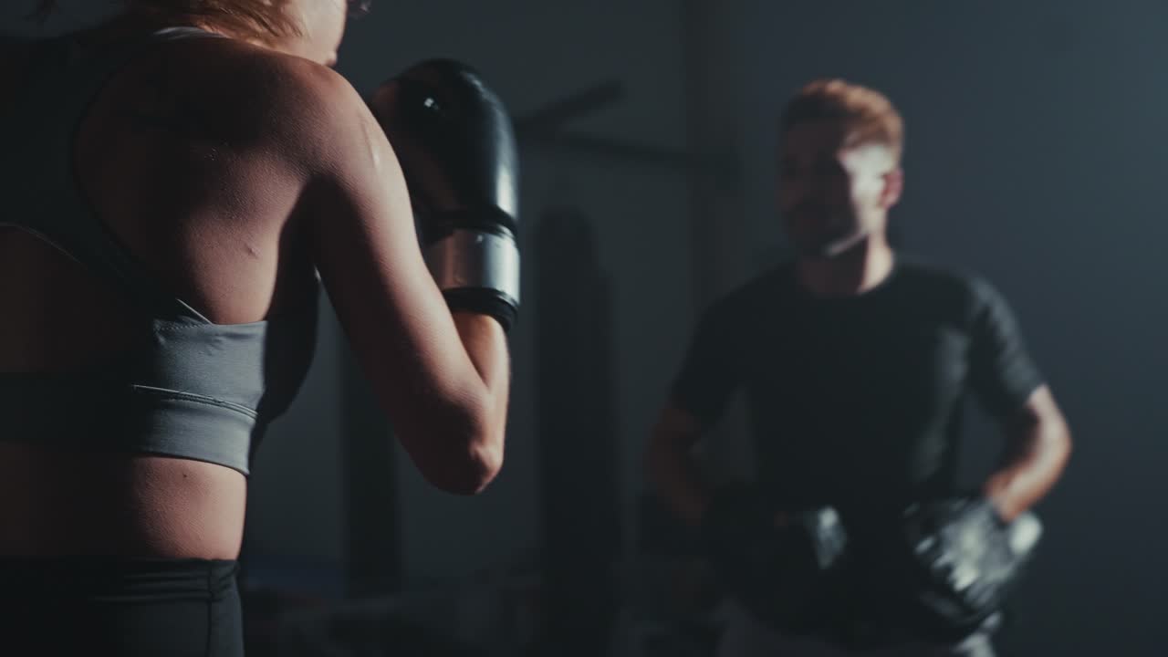 Boxeadora Determinada Treinando com Treinador em Academia Escura.