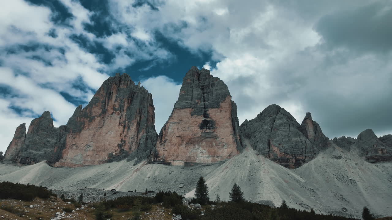 Impressive view of Tre Cime di Lavaredo peaks in the Dolomites, Italy, with white clouds moving across the blue sky