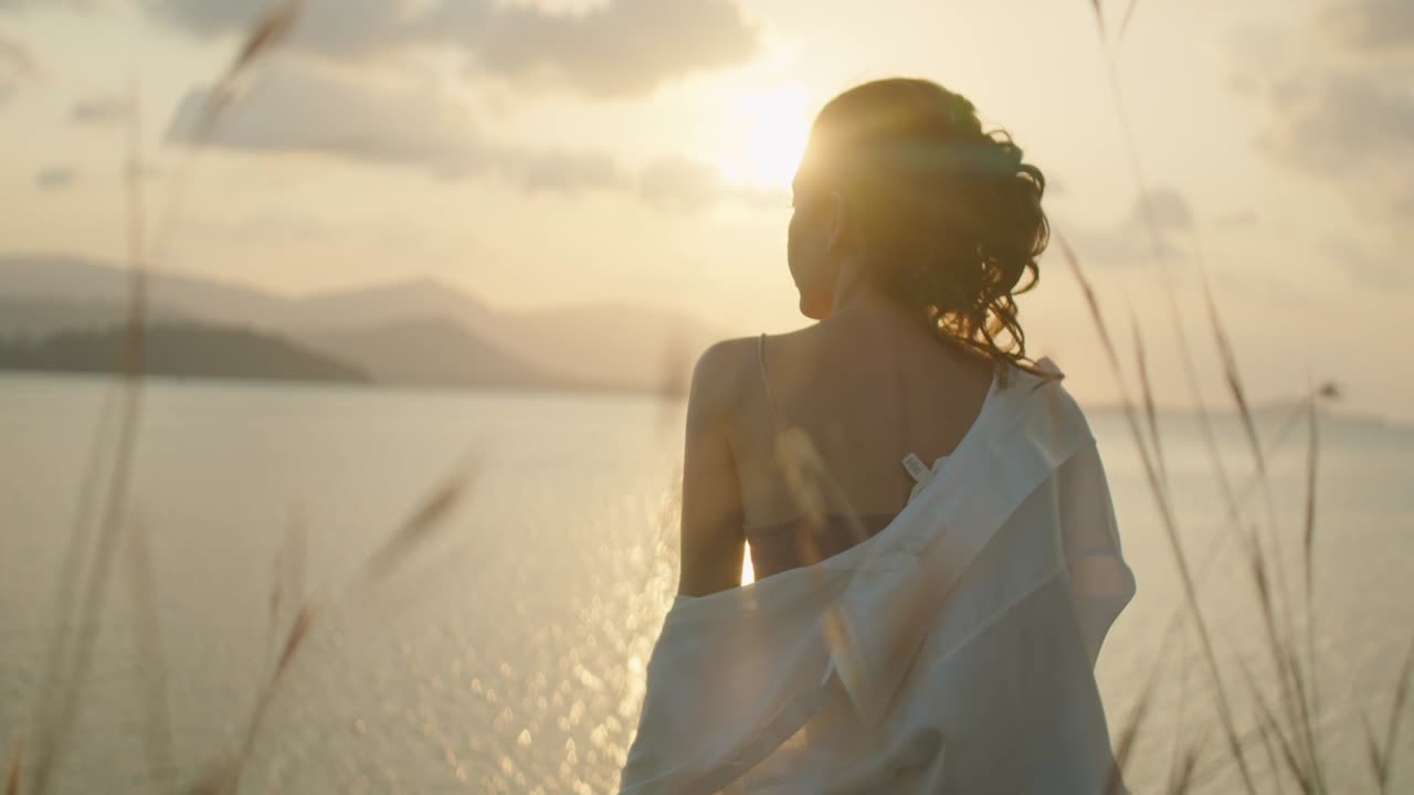 Woman Contemplating the Sunset Over the Water