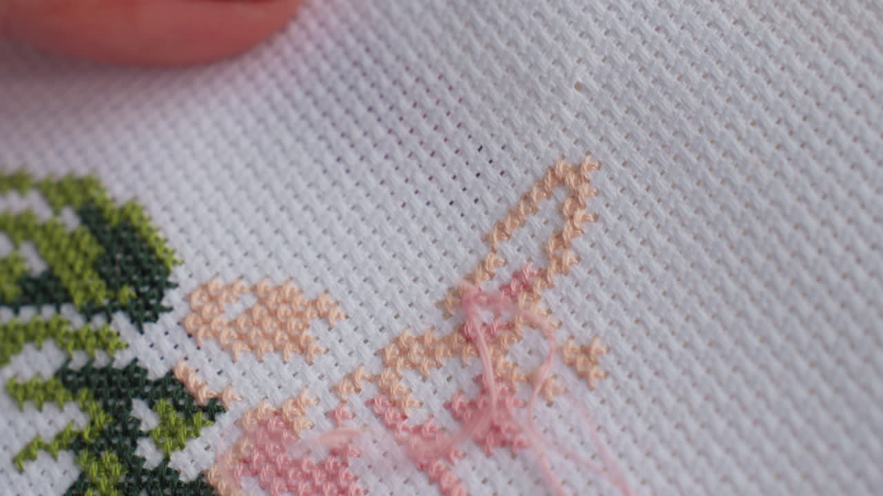Extreme close up skilled person embroidering fabric tree like design , delicate needlework creating detailed texture, colorful thread pattern forming artistic handmade craft on white cloth