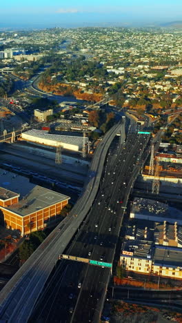 lively traffic on the highways of los angeles at daytime. sunny panorama of the city at backdrop of mountains. top view. vertical video