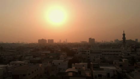 aerial over of karachi skyline with mosque minaret against golden orange sunset