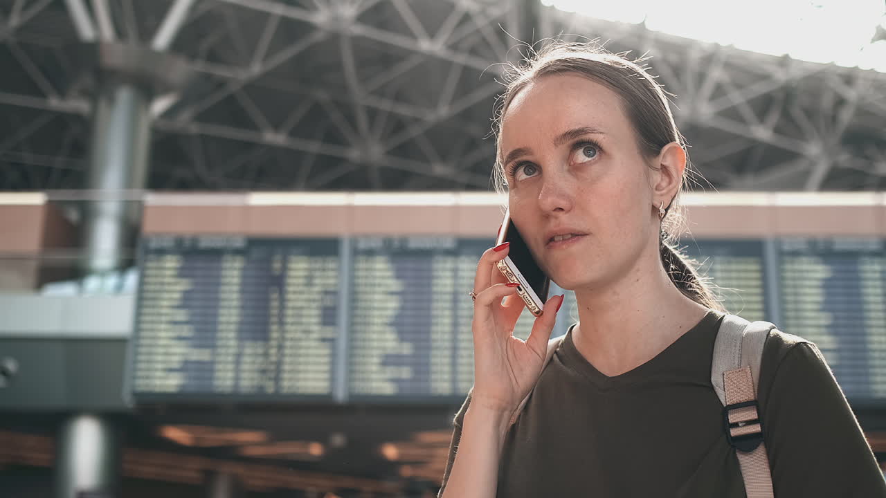 Donna che parla al telefono discutendo i dettagli del suo viaggio e prenotando un'auto dopo l'atterraggio. Prenota una stanza d'albergo a causa di ritardi del volo