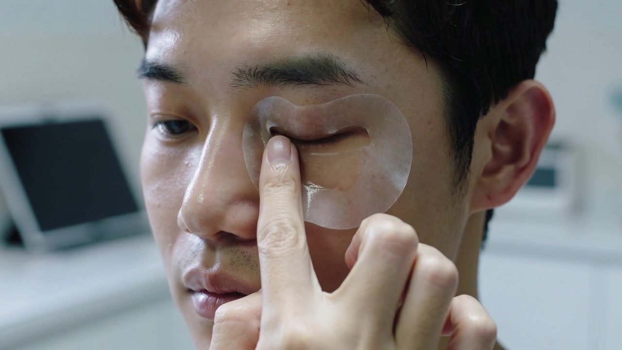 Bringing undereye gel patch close pro placing, smoothing under right eye in clinic pressing to seal
